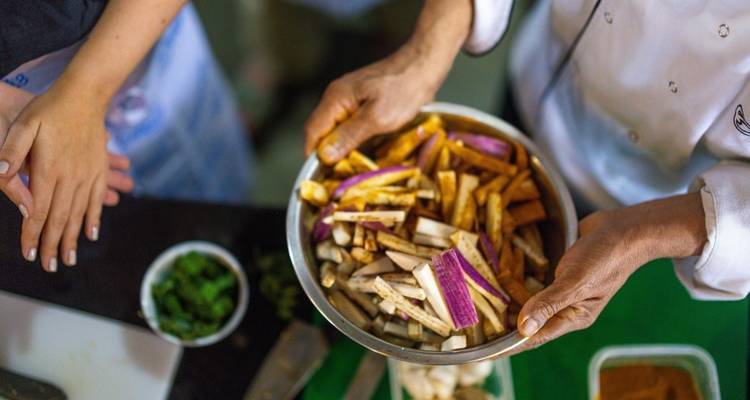 Hands preparing vegetables in a cooking class.