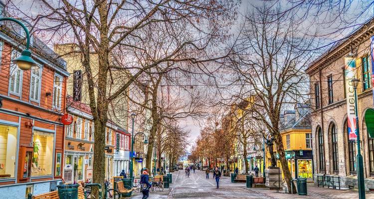 City street lined with bare trees and people walking.