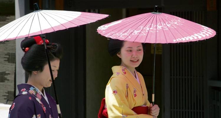 Zwei Personen in traditioneller japanischer Kleidung mit Sonnenschirmen.