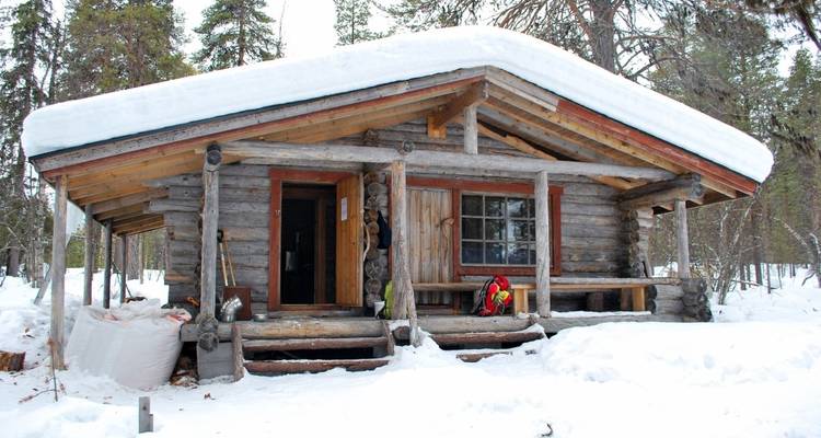 Chalet en rondins dans un paysage de forêt enneigée.