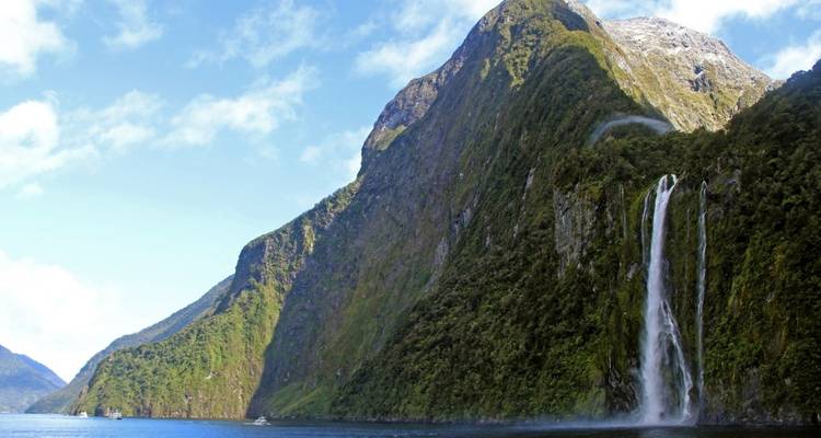 Large waterfall cascading down a mountain into a fjord.