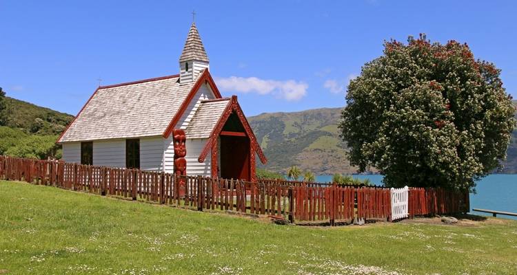 Charming white church with red roof near a lake.