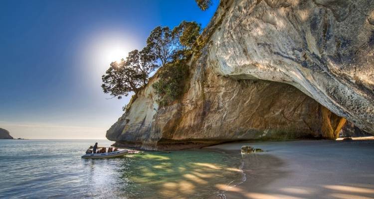 Serene beach with a cave and people in a boat.