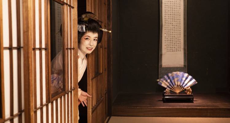 Geisha asomándose desde detrás de un biombo en un entorno tradicional