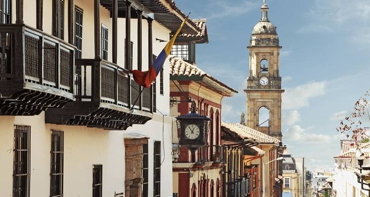 Vista histórica de la ciudad con torre del reloj y bandera colombiana.