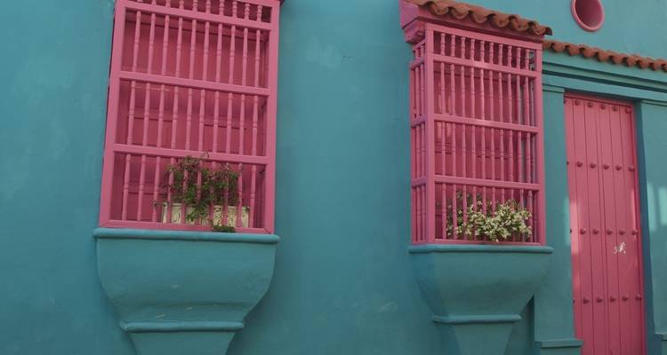 Fachada pintada con colores vivos con ventanas rosas.