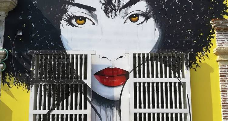 Mural brillante del rostro de una mujer en la fachada de un edificio.