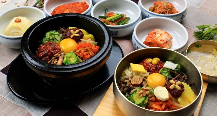Koreanische Gerichte einschließlich Bibimbap und Kimchi serviert in Schüsseln.