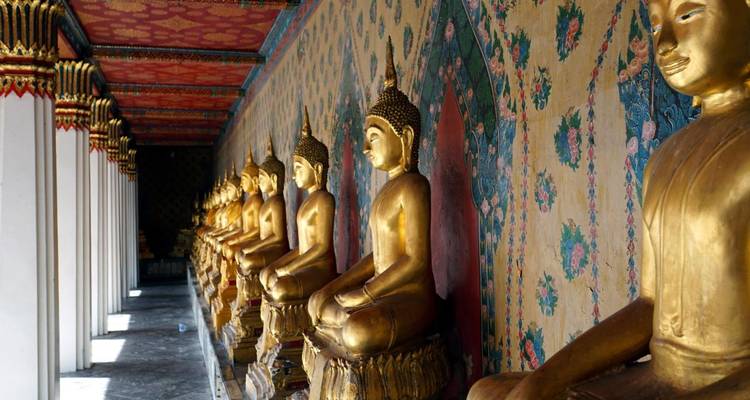 Statues dorées de Bouddha dans un couloir décoré d'un temple.