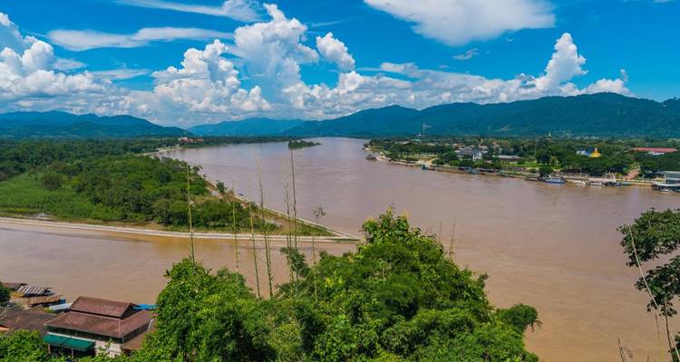 Paysage fluvial avec montagnes et ciel bleu clair.