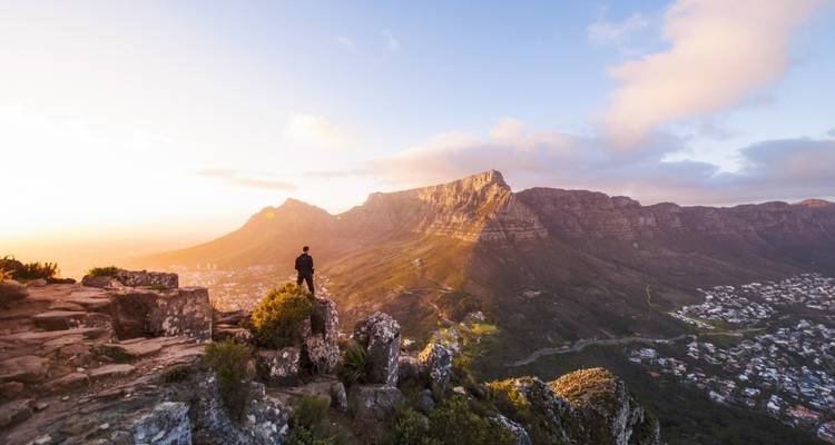 Person standing on a mountain cliff at sunrise.