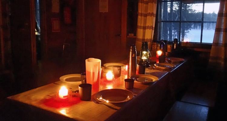 Table à manger éclairée aux bougies dressée pour le dîner dans une cabane.