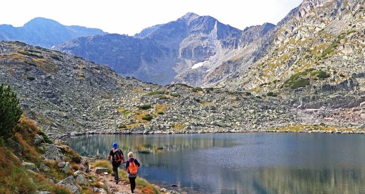 Hikers walking near a lake in a mountainous region.