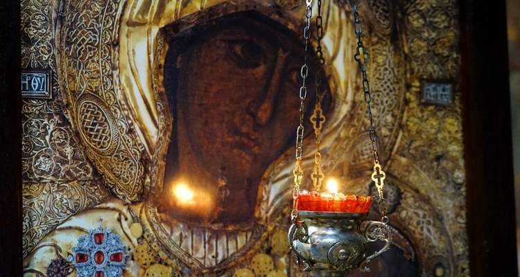 Un icono religioso ornamentado con una vela encendida frente a él.
