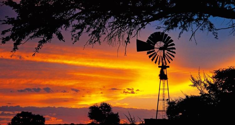 Silueta de un molino de viento contra un cielo vibrante de atardecer.