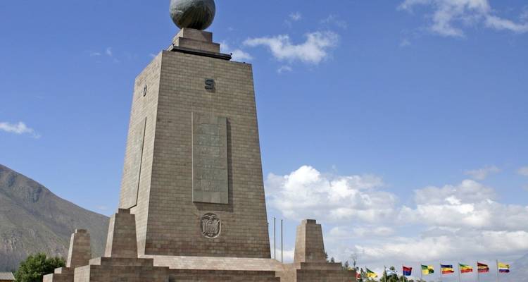 Monumento en el ecuador con banderas sudamericanas cercanas.