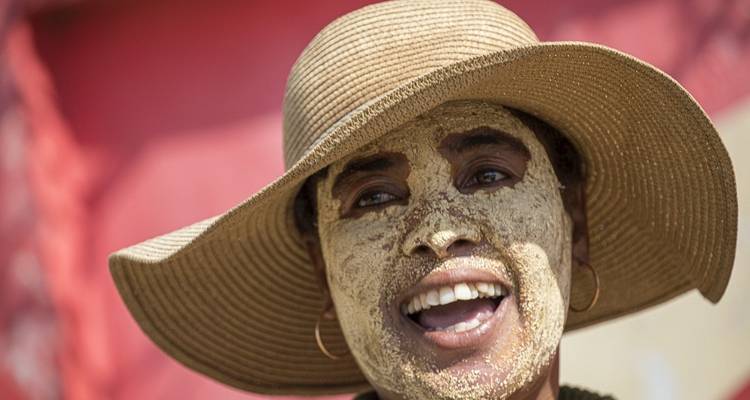 Persona con mascarilla facial y sombrero de ala ancha sonriendo.