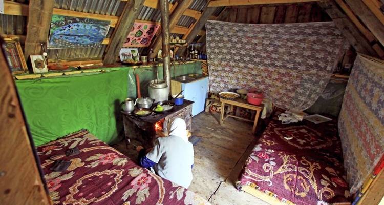 Cozy interior of a traditional hut with someone cooking on a small stove.