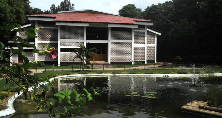 Ein Gebäude mit einem Teich in einer Gartenanlage.