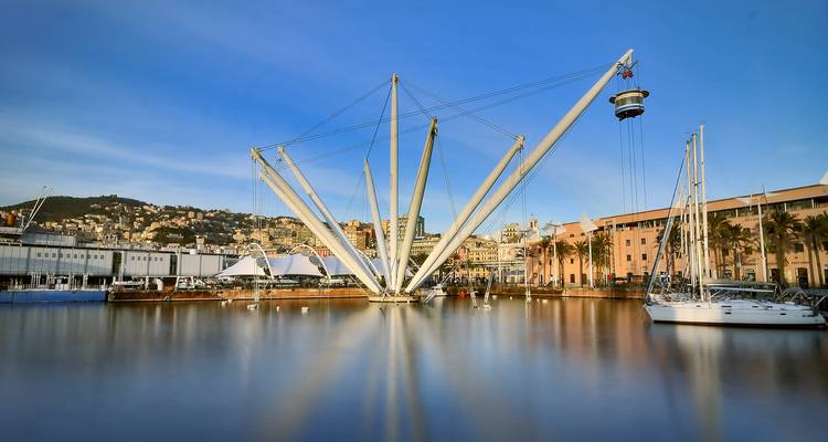 Die moderne Bigo-Hebevorrichtung und der Yachthafen im Alten Hafen von Genua spiegeln sich im glatten blauen Wasser wider.