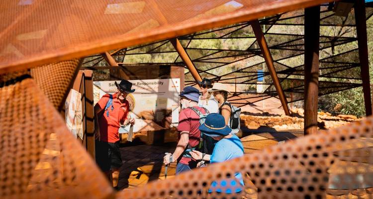 Group of tourists listening to a guide at a visitor center.