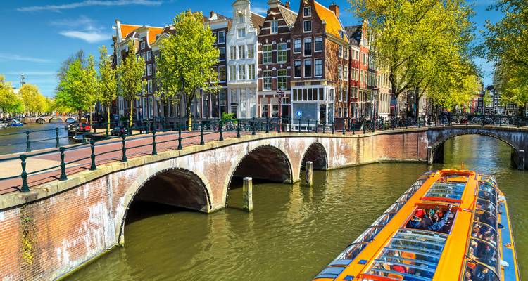 Tourist boat on a canal surrounded by traditional Dutch architecture.