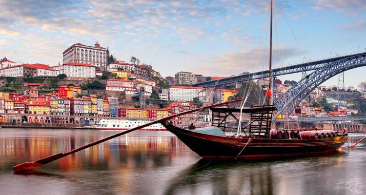 Paysage urbain de Porto avec un bateau traditionnel sur la rivière au premier plan.