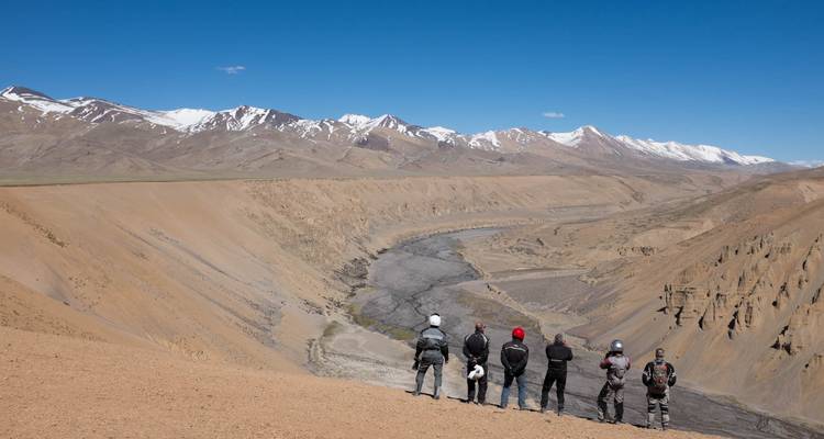 Motocyclistes contemplant une vue panoramique sur une vallée de montagne.