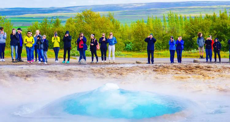A group of tourists viewing a geothermal geyser eruption