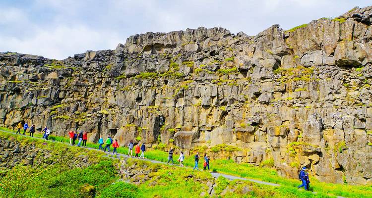 Tourists walking along a rock wall pathway