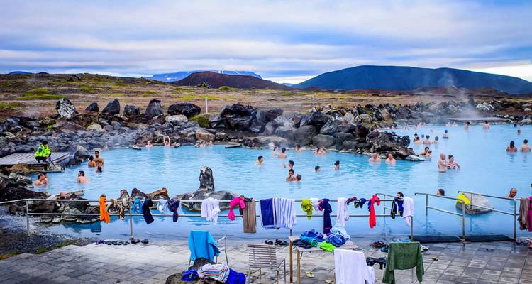 People enjoying a hot spring with a mountainous backdrop