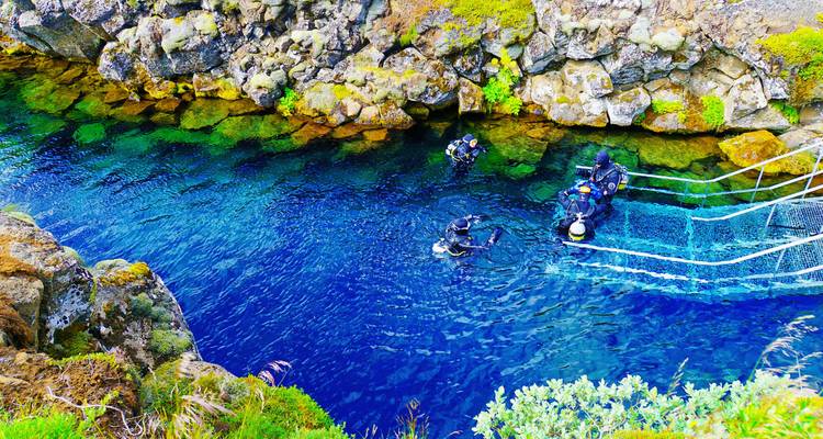 Divers exploring a clear blue water fissure
