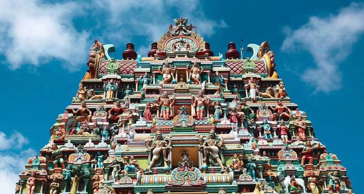 Nahaufnahme eines kunstvoll gestalteten Tempelturms vor einem blauen Himmel.