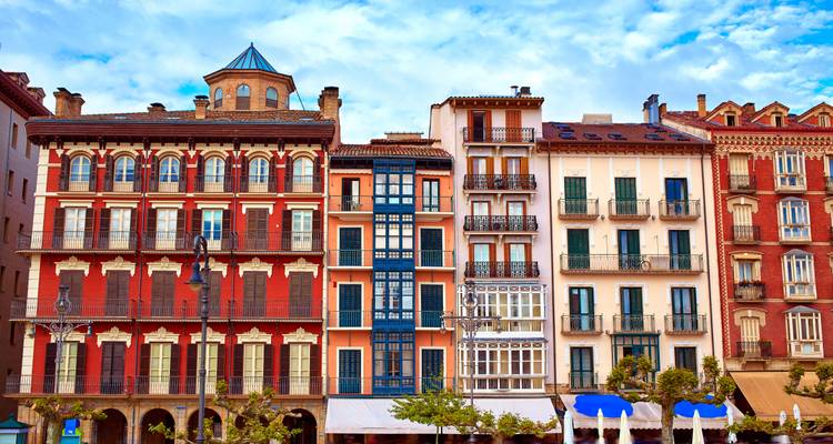 Een rij kleurrijke traditionele gebouwen met balkons en een levendige hemel erboven.