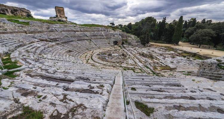 Overblijfselen van een oud amfitheater met bewolkte luchten.