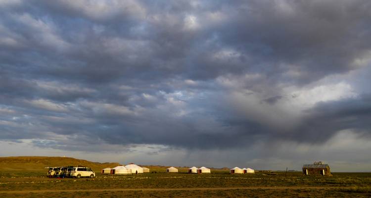 A series of traditional Mongolian yurts under a dramatic sky.