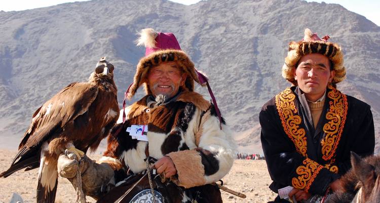 Two men in traditional attire with a bird of prey.
