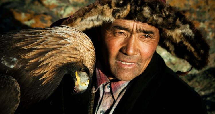 A man in traditional attire holding a bird of prey.