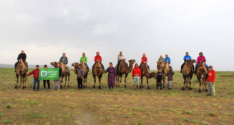 A large group of people with camels in a desert area.
