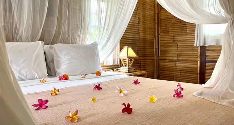 Close-up van een versierd bed in een kamer met bamboewanden.