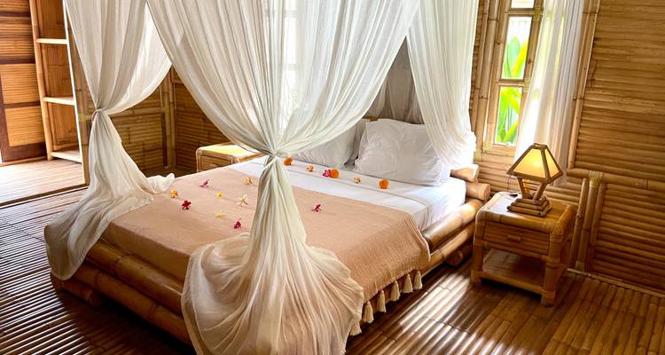 Kamer met een versierd bed en bamboe-esthetiek.