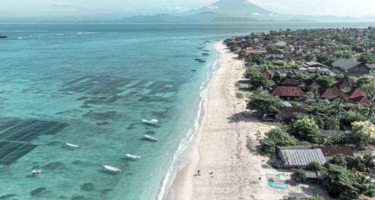 Luchtfoto van een strand met boten en kustvilla's.
