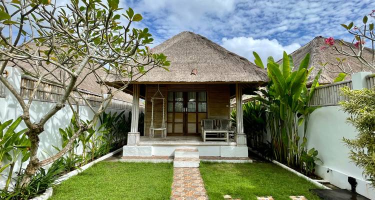 Traditionele bungalow met een rieten dak en een tuin.