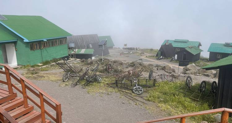 Scattered wheelbarrows near mountain huts in a foggy setting.