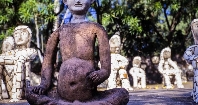 Stenen sculpturen in een tuinomgeving met de nadruk op de centrale figuur.