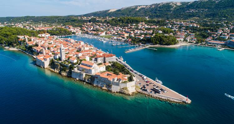 Vue aérienne d'une ville côtière avec des bâtiments historiques et un port de plaisance.
