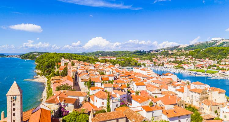 Vue d'une ville côtière avec des bâtiments aux toits rouges et une baie.