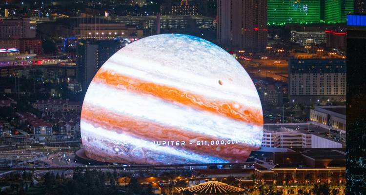 Die Sphere in Las Vegas, beleuchtet mit einer lebendigen Jupiter-Projektion vor der Kulisse der Stadtlichter.