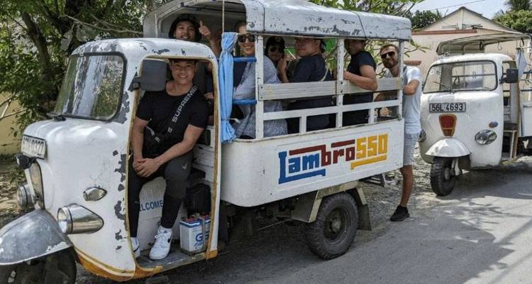 Travellers ride in a vintage three-wheeled Lambro tuk-tuk during a countryside excursion.