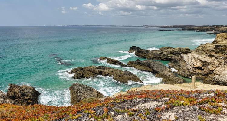 Rocky coastline with turquoise sea under a partly cloudy sky.